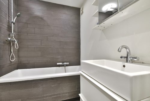 Bathroom interior with unusual tiles on the wall and a large bathtub