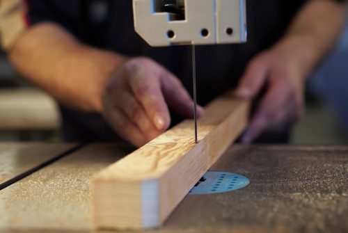 Handwork, carpentry concept, woodworking. Carpenter working in in factory atelier. Joiner labourer cuts wooden plank on jigsaw machine. High quality photo